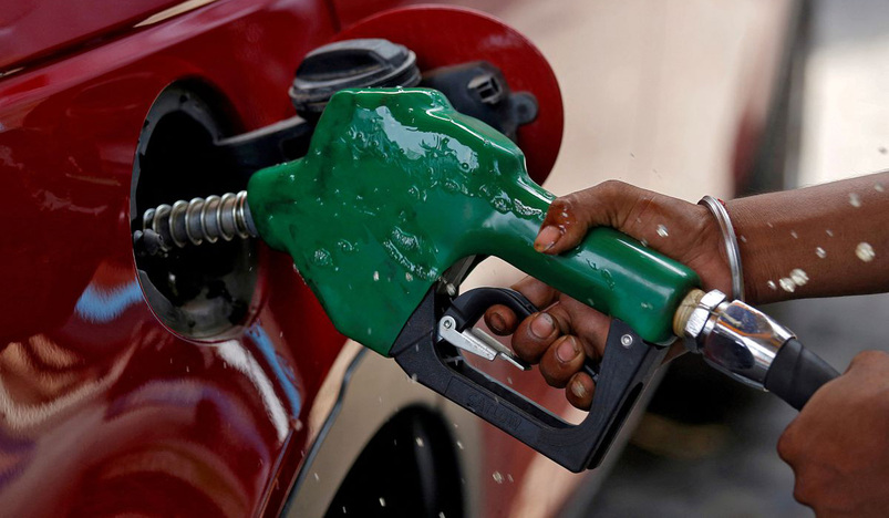 A worker holds a nozzle to pump petrol into a vehicle